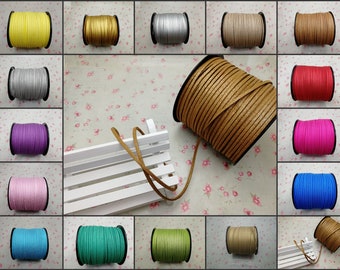 May include: Assortment of spools of faux leather cord in various colors, including yellow, silver, beige, brown, red, pink, purple, blue, green, and turquoise. The cords are wound around spools and displayed on a white wooden bench.