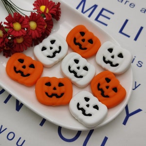 Op de afbeelding: Acht Halloween-thema pumpkin-vormige decoraties. Vier zijn oranje met zwarte jack-o'-lantern gezichten en vier zijn wit met zwarte jack-o'-lantern gezichten.