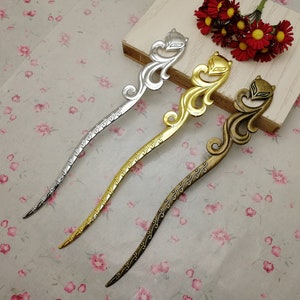 Puede incluir: Tres palitos decorativos para el pelo con un diseño de zorro. Los palitos son plateados, dorados y bronce.