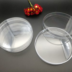 May include: Three clear plastic round containers with lids. The containers are stacked on top of each other. The lids are separate.