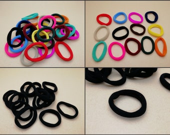 May include: A variety of colorful hair ties in a pile, along with a separate pile of black hair ties.