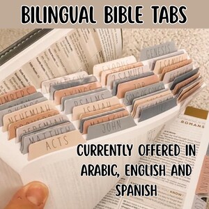 May include: A set of bilingual Bible tabs with the text "BILINGUAL BIBLE TABS" at the top. The tabs are in various colors and labeled with book names like Genesis and Romans. The text "CURRENTLY OFFERED IN ARABIC, ENGLISH AND SPANISH" is also visible.