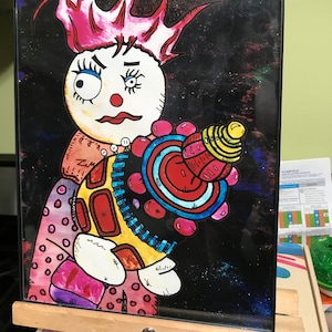 May include: A colorful illustration of a cartoon character with pink hair holding a red, blue, and yellow space-themed object. The background is a dark blue with white stars.