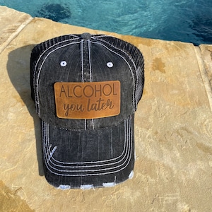 May include: Black denim trucker hat with a brown leather patch that says "ALCOHOL you later".