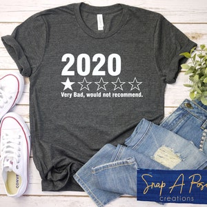 Puede incluir: Una camiseta gris oscura con un gráfico blanco que dice "2020" y tiene una calificación de una estrella. El texto debajo de la calificación dice "Muy malo, no lo recomendaría."
