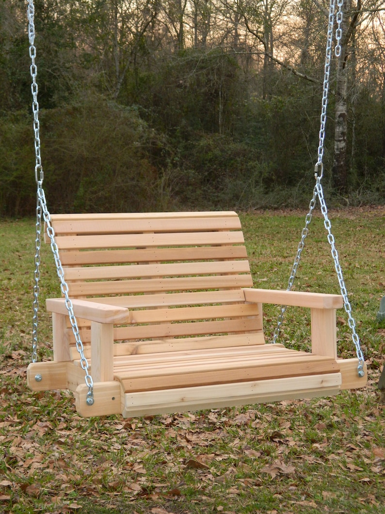 Puede incluir: Un columpio de madera con respaldo y asiento de listones, y dos reposabrazos. El columpio est&aacute; colgado de dos cadenas unidas a un marco de metal.