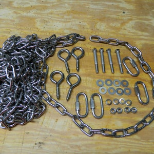 May include: A set of silver-toned hardware for hanging a swing or other outdoor equipment. The set includes a chain, two eye hooks, four screws, eight washers, four nuts, and two quick links.