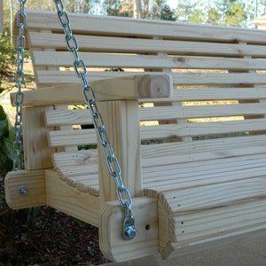 May include: A wooden porch swing with slatted back and seat, hanging from two silver chains. The swing is made of unfinished wood and has a simple design.