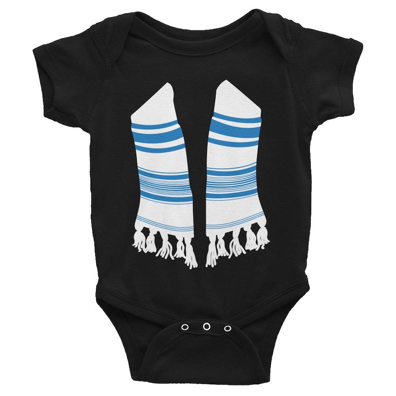 Pu&ograve; includere: Body per neonati nero con un design grafico bianco e blu che ricorda un tallit. Il design include strisce blu e nappe bianche. Il body ha tre chiusure a scatto sul fondo.