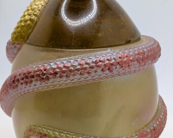 May include: A decorative jar with a brown lid and a golden-yellow body. A textured, iridescent snake winds around the jar. The lid has a golden-yellow knob. The jar has a pearlescent finish.