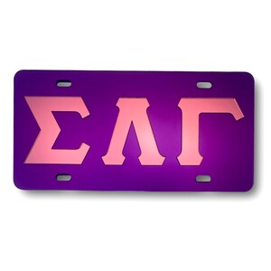 May include: Purple license plate with pink letters spelling "ΣΛΓ".