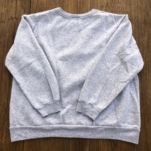 May include: A gray sweatshirt with long sleeves and a crew neck.
