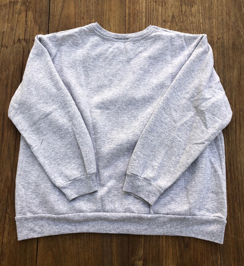 May include: A gray sweatshirt with long sleeves and a crew neck.