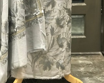 May include: A light gray fabric with a silver floral pattern. The fabric is draped over a wooden stand.