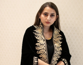May include: A black velvet shawl with gold embroidery. The shawl has a paisley pattern and is trimmed with a gold border.