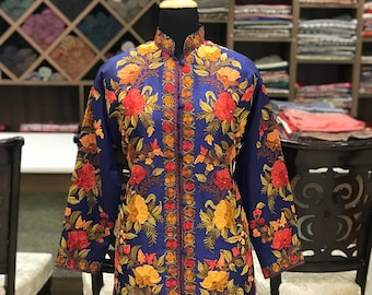 May include: A long, blue embroidered jacket with a mandarin collar and floral patterns in shades of red, orange, and yellow.