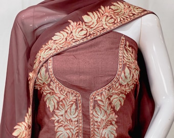 May include: A deep maroon sleeveless tunic featuring intricate gold thread embroidery around the neckline and a matching sheer maroon shawl draped over the shoulder, also adorned with detailed gold leaf-patterned embroidery along the edges.