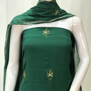 May include: A dark green dress with gold leaf embroidery. The dress has a simple, elegant design and is perfect for a variety of occasions.