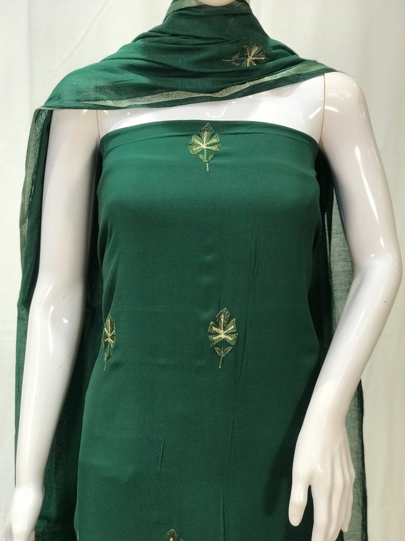 May include: A dark green dress with gold leaf embroidery. The dress has a simple, elegant design and is perfect for a variety of occasions.