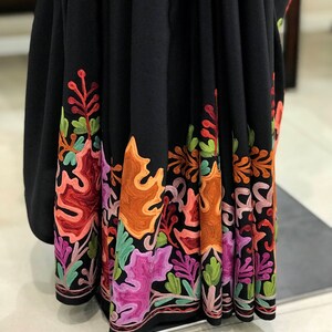 Peut inclure: Sari noir avec un motif floral brod&eacute; color&eacute; autour du bord inf&eacute;rieur. La broderie est r&eacute;alis&eacute;e avec du fil orange, rose, vert et marron.