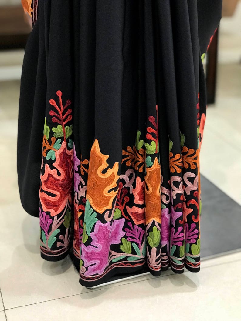 Peut inclure: Sari noir avec un motif floral brod&eacute; color&eacute; autour du bord inf&eacute;rieur. La broderie est r&eacute;alis&eacute;e avec du fil orange, rose, vert et marron.