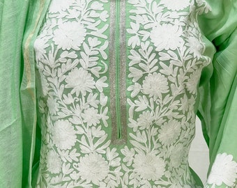 May include: A light green cotton kurta with white embroidery featuring floral designs. The kurta has a silver trim along the neckline and sleeves.
