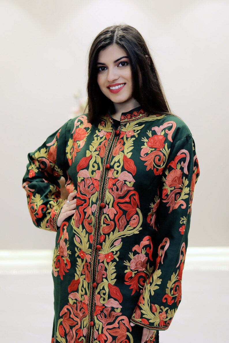 May include: A long, dark green embroidered jacket with a mandarin collar and floral patterns in shades of red, pink, and gold.