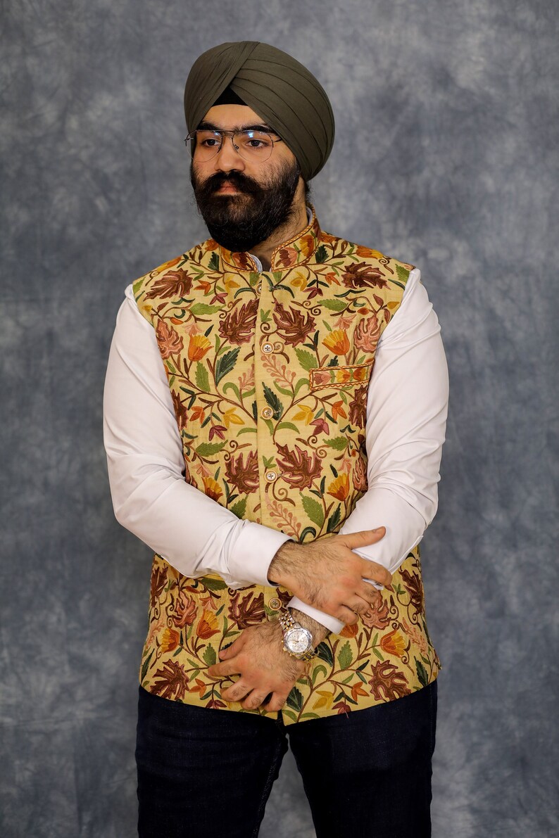 Peut inclure: Un homme portant une chemise blanche, un gilet &agrave; motifs floraux et un turban vert. Il porte une montre au poignet gauche.