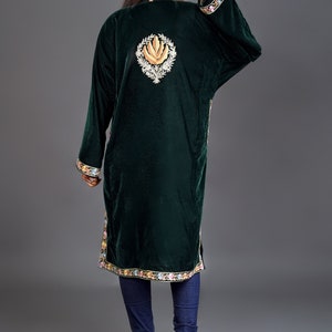 May include: A dark green velvet tunic featuring long sleeves and a high neckline. The back displays a large, central embroidered floral motif in gold and white, with colorful floral embroidery along the sleeve cuffs and the bottom hemline.