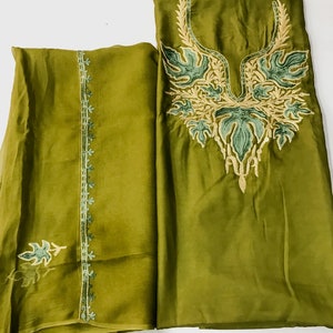 May include: A green two-piece outfit with embroidery. The top has a V-neckline and floral embroidery. The bottom has a straight cut and a floral border.