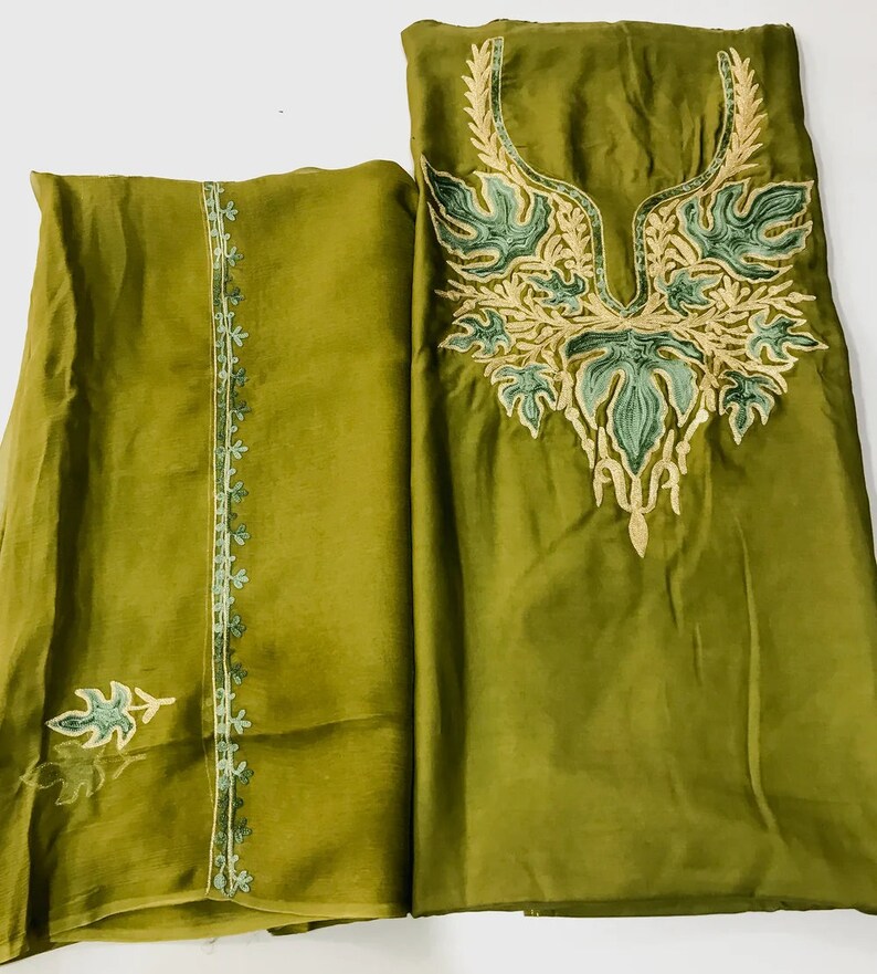May include: A green two-piece outfit with embroidery. The top has a V-neckline and floral embroidery. The bottom has a straight cut and a floral border.