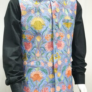 May include: A light blue vest with a floral embroidery pattern. The vest has a mandarin collar and a button closure.