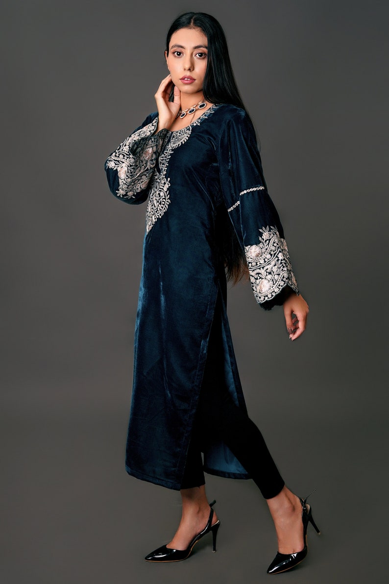 May include: A teal velvet tunic with intricate embroidery on the sleeves and neckline. The long-sleeved tunic features a high slit and is paired with black pants and heels. The outfit is elegant and suitable for special occasions.