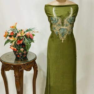 May include: A green fabric with a decorative embroidered neckline. The embroidery is in shades of green and gold.