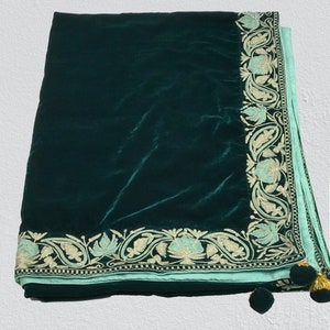 May include: A dark green velvet shawl with a light blue embroidered border and gold tassels.