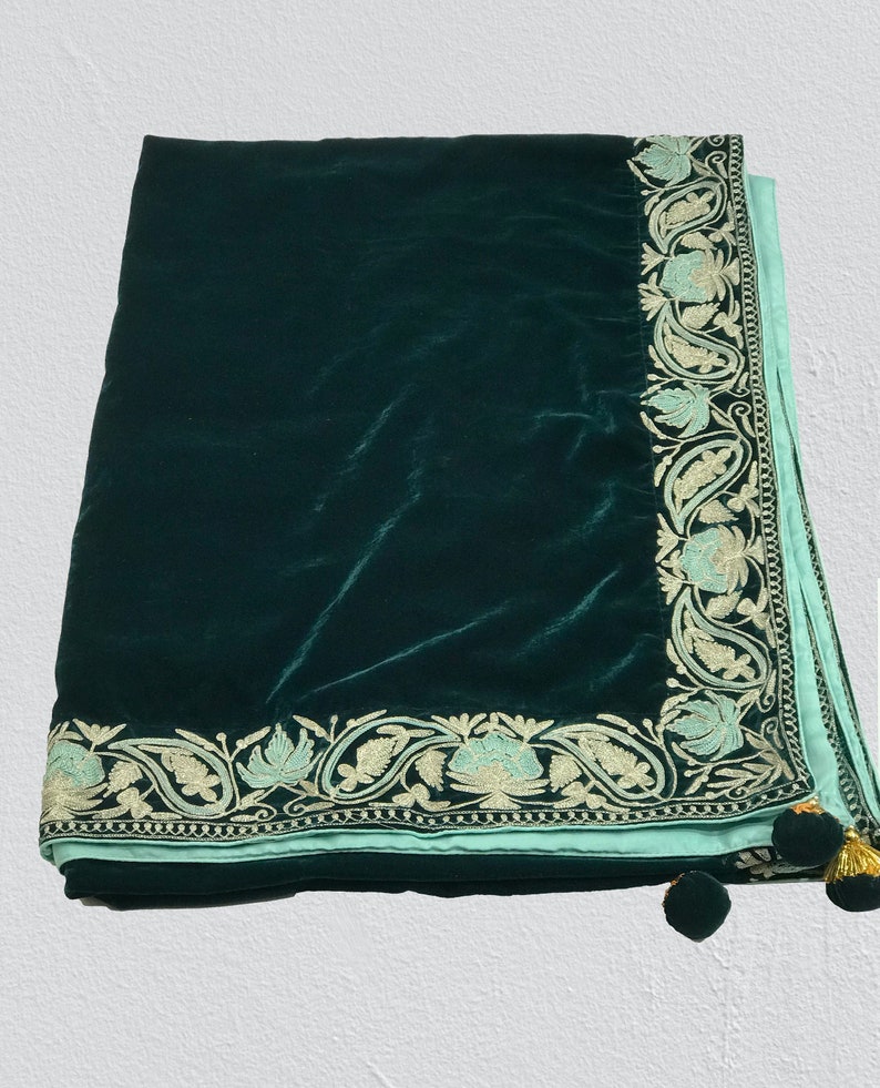 May include: A dark green velvet shawl with a light blue embroidered border and gold tassels.