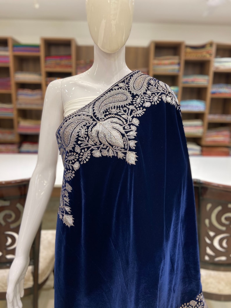 May include: A navy blue velvet shawl with silver embroidery. The embroidery features a paisley design and floral motifs.