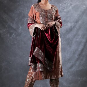May include: A copper-colored velvet tunic and matching trousers featuring intricate silver embroidery around the neckline and cuffs, paired with a deep burgundy velvet shawl that has a wide silver embroidered border along the edges.