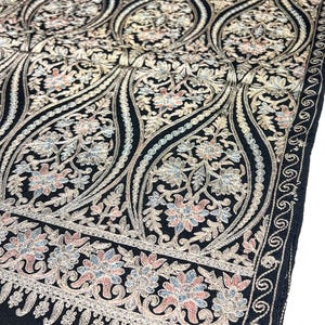 May include: A black shawl with intricate gold embroidery featuring a floral paisley pattern. The shawl has a delicate border with a repeating design.