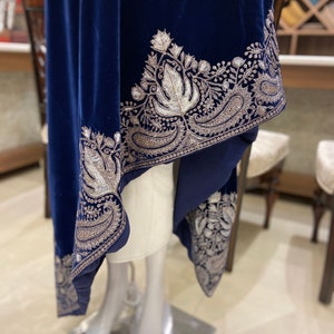 May include: A navy blue velvet shawl with a silver embroidered border featuring floral and paisley designs.