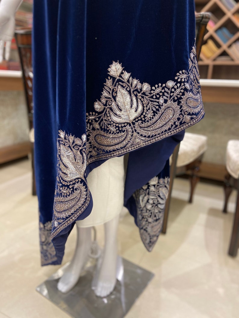 May include: A navy blue velvet shawl with a silver embroidered border featuring floral and paisley designs.