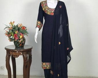 May include: A navy blue salwar kameez with floral embroidery on the neckline, sleeves, and hem. The outfit includes a matching dupatta with floral embroidery.