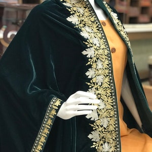 May include: A dark green velvet shawl with gold and silver embroidery. The shawl has a floral pattern and is trimmed with a gold and silver border.