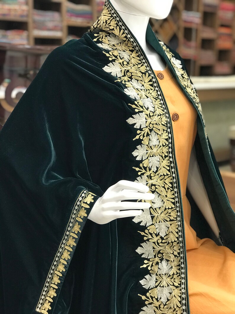 May include: A dark green velvet shawl with gold and silver embroidery. The shawl has a floral pattern and is trimmed with a gold and silver border.