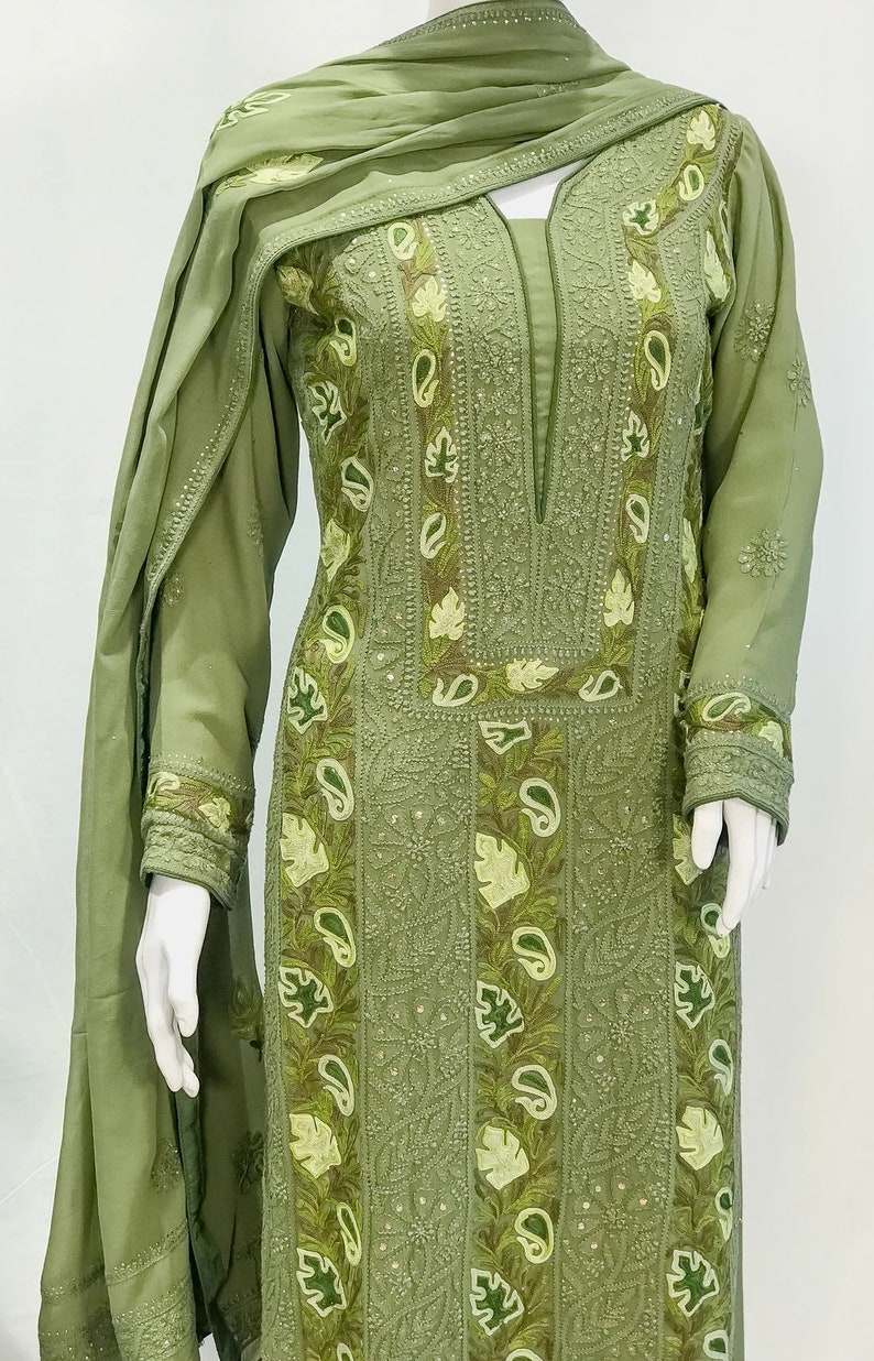 May include: An olive green long-sleeved tunic and matching scarf set featuring intricate tonal embroidery, decorative leaf and paisley appliqu&eacute; patterns, and subtle sequin embellishments along the neckline, cuffs, and front panel.