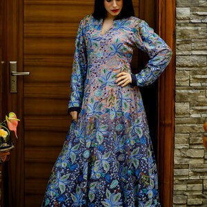 May include: A long, flowing dress with a floral print in shades of blue, pink, and green. The dress has a V-neckline and long sleeves.