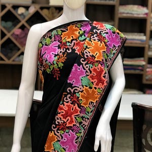 Peut inclure: Sari noir avec des motifs floraux brod&eacute;s color&eacute;s. La broderie pr&eacute;sente une vari&eacute;t&eacute; de couleurs, notamment le rose, l'orange, le vert et le rouge.