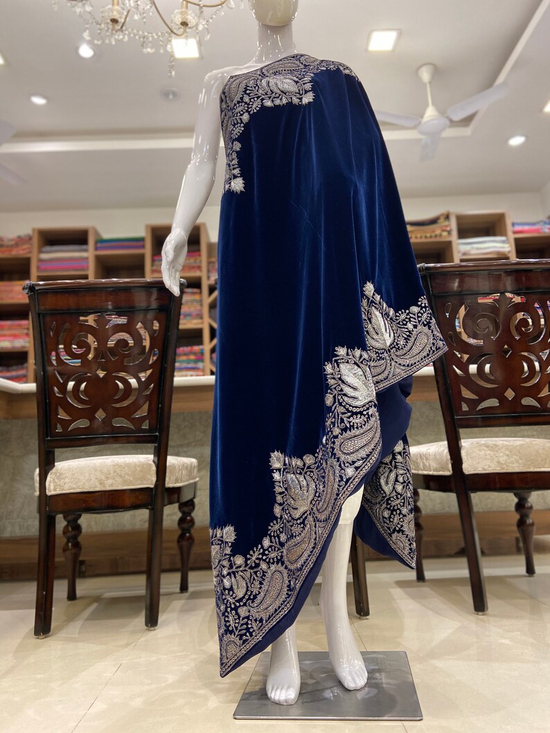 May include: A navy blue velvet shawl with silver embroidery. The shawl is draped over a mannequin and has a paisley design.