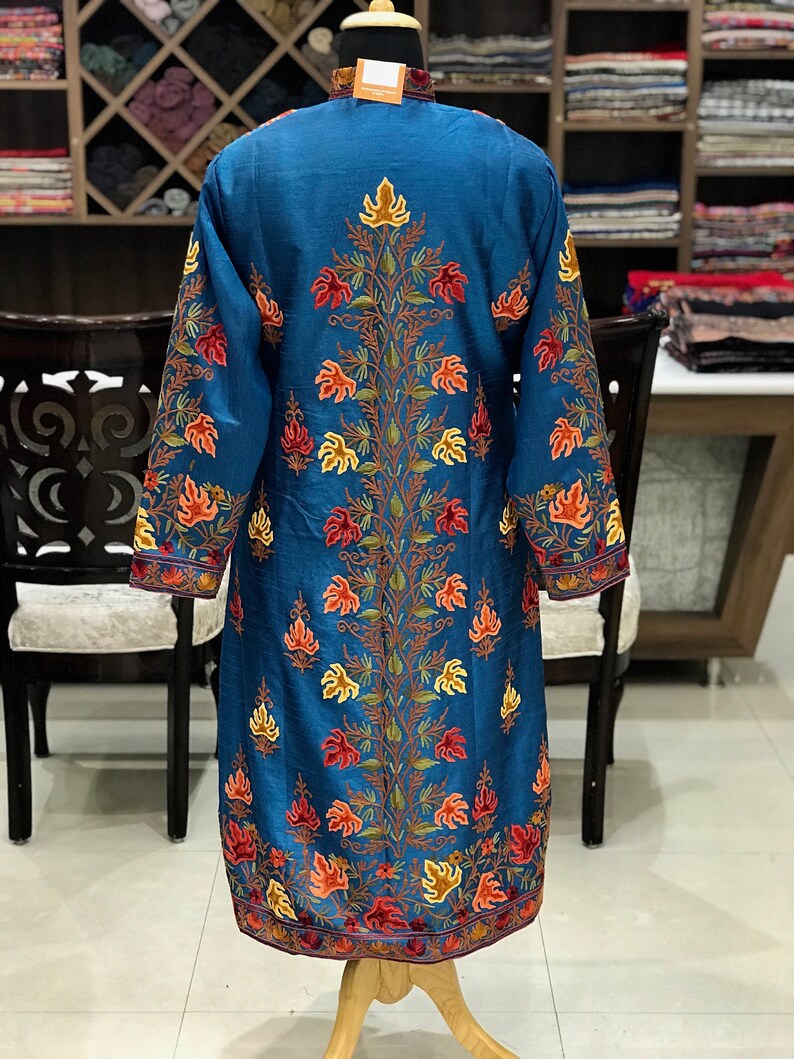 May include: A long, blue silk robe with intricate floral embroidery in shades of orange, red, and yellow. The robe has a high neckline and long sleeves.