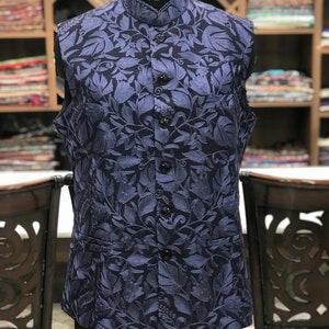 Pu&ograve; includere: Un gilet blu navy senza maniche con un motivo floreale. Il gilet ha un colletto alla coreana e una chiusura con bottoni.